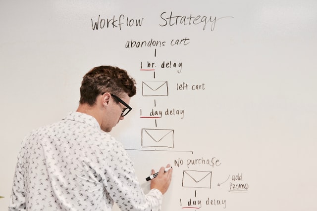 man writing down workflow strategy of a project on white board
