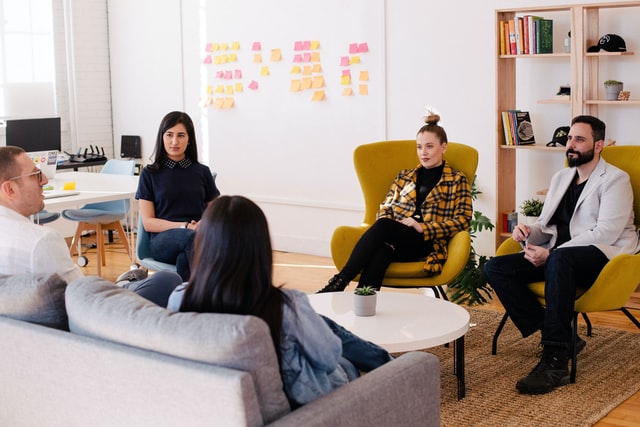 people sitting in a conference room facing each other and brainstorming