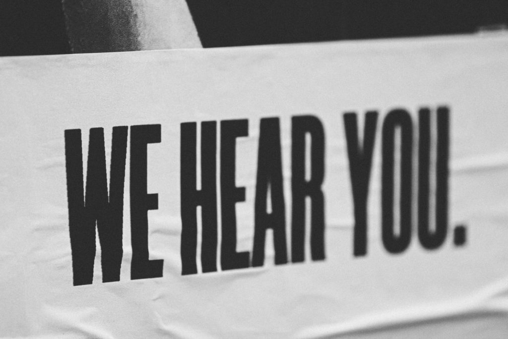 black and white banner that reads we hear you