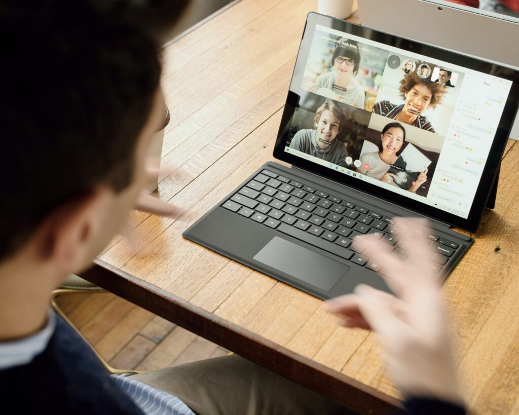 man having a group video conference call with teammates while working remotely at home