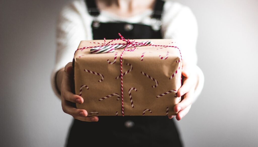 Woman holding out a gift with holiday warpping