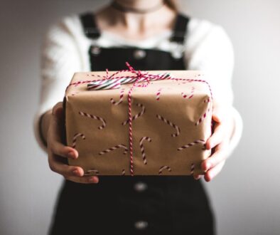 Woman holding out a gift with holiday warpping