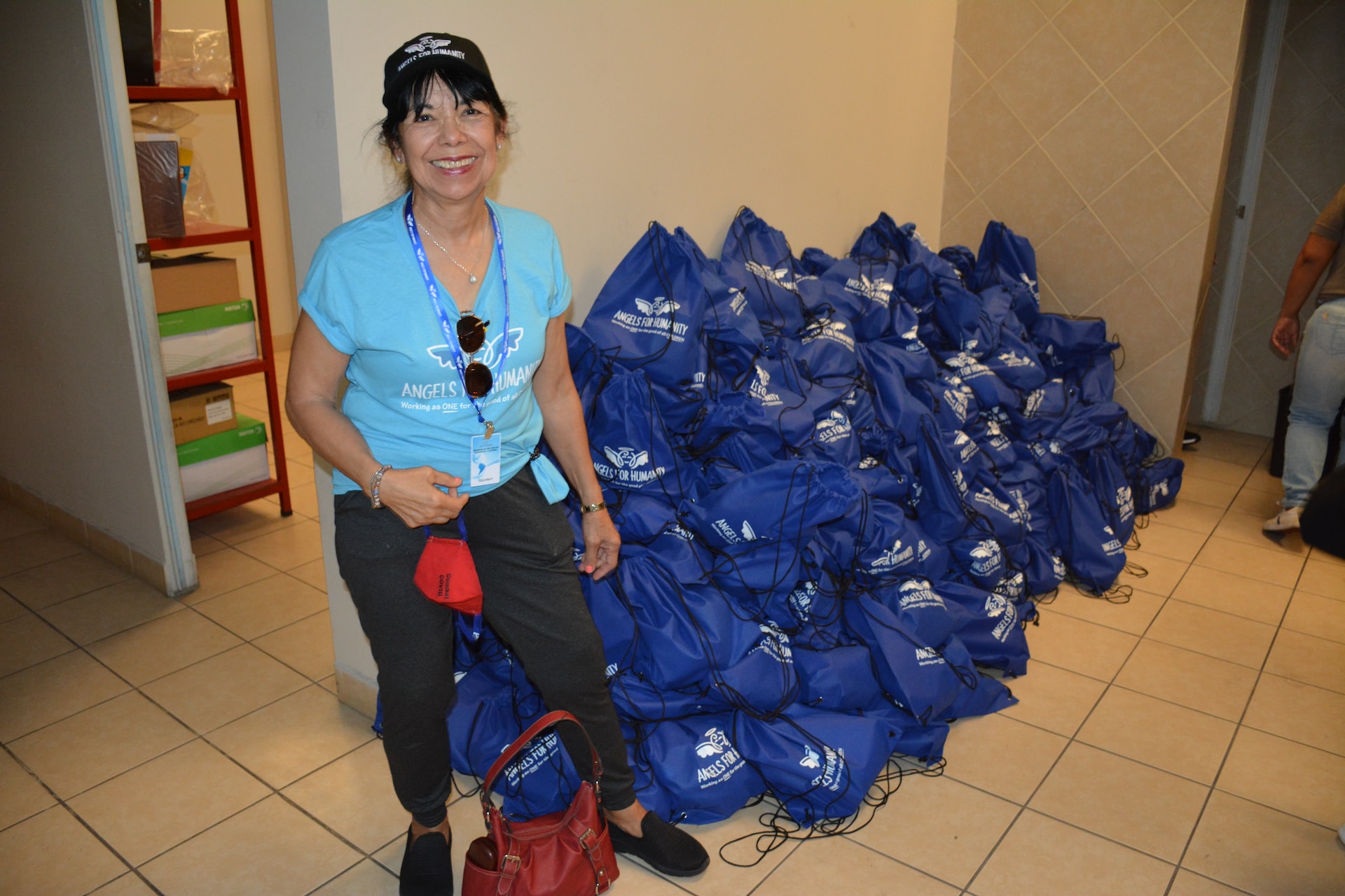 Smiling volunteer sitting near a large pile of donations.